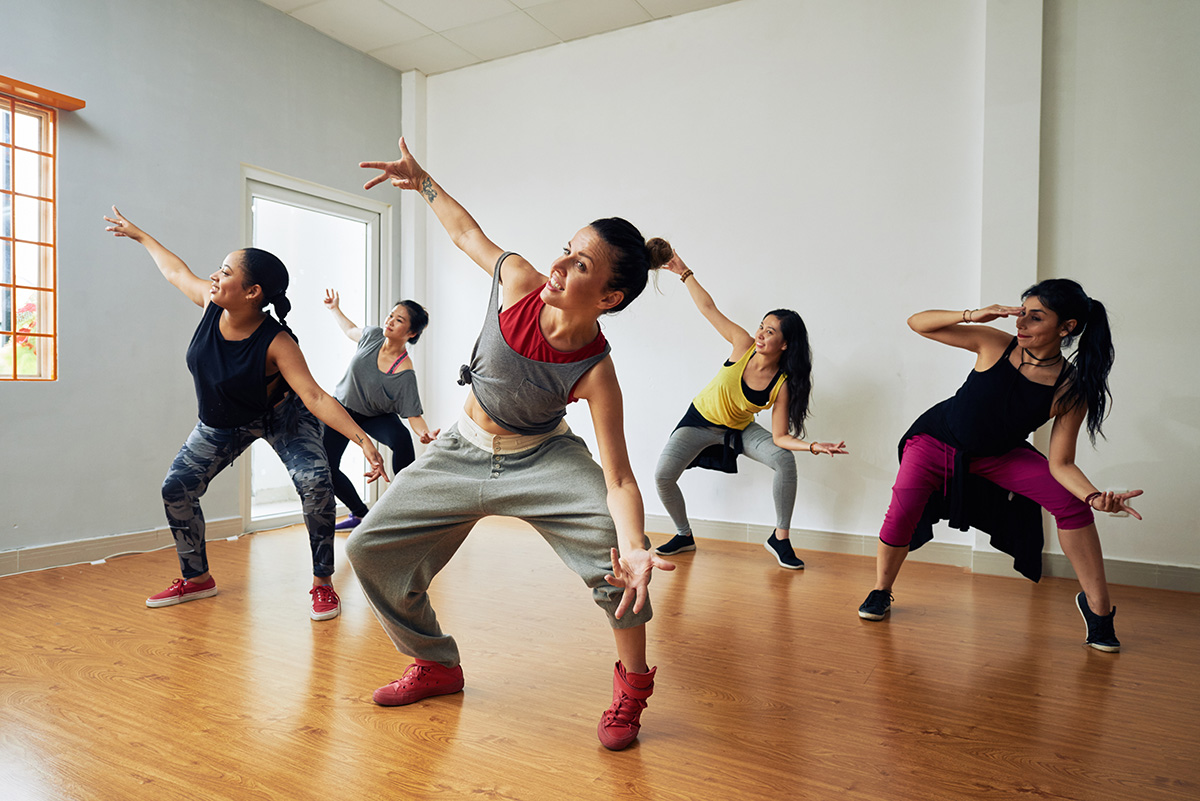 Group of energetic hip-hop dancers focused on training while gathered together in spacious dance hall