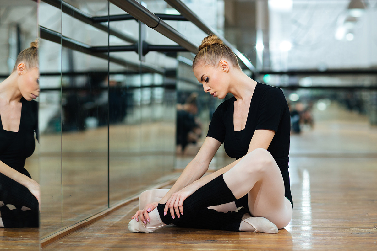 Injured ballerina in pointes sitting on the floor in ballet class